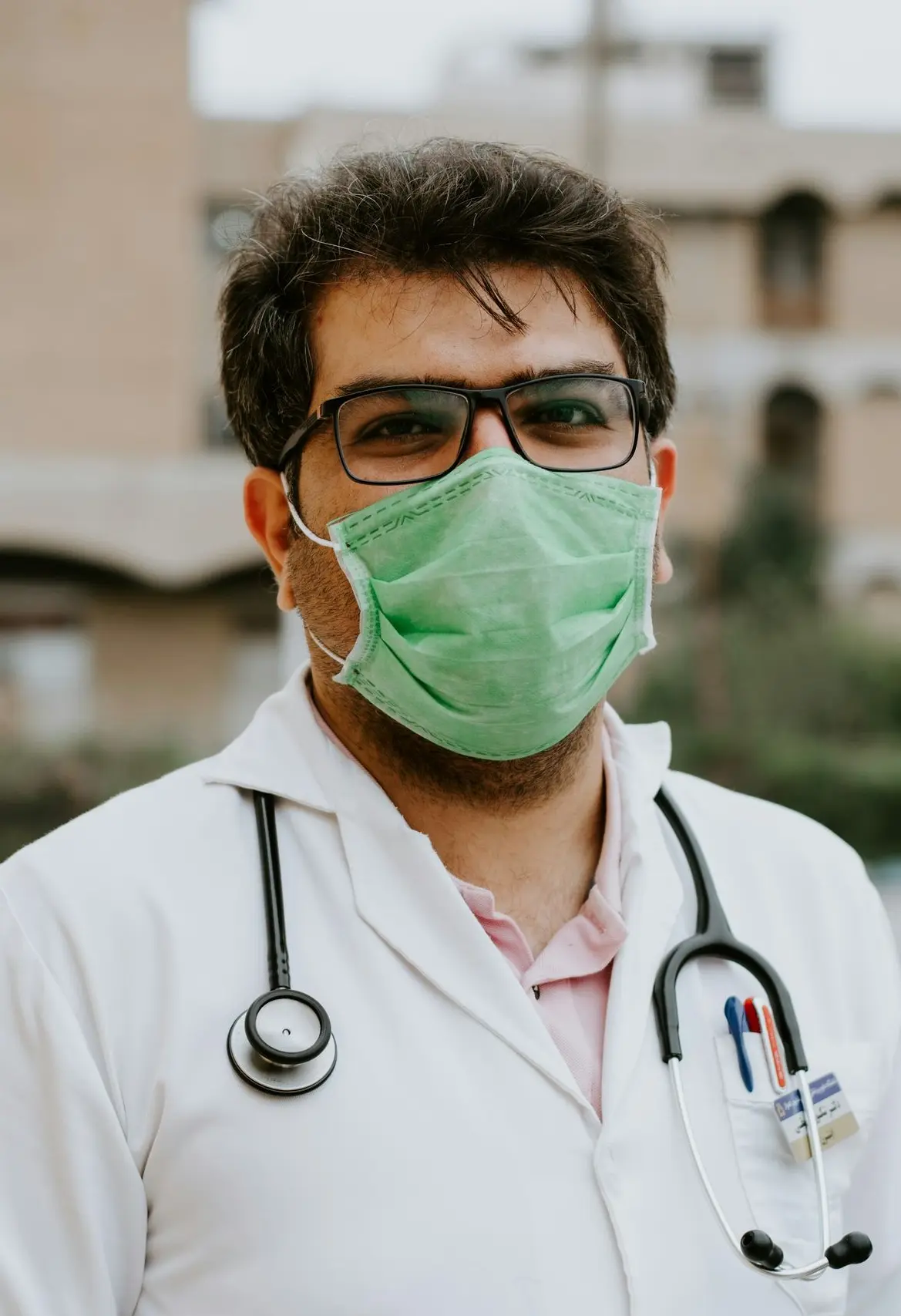 man in white scrub suit wearing green mask